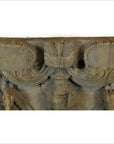 Brown sheesham wood carving sculpture close-up with intricate patterns and winged details, indoors.
