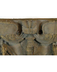 Brown sheesham wood carving sculpture close-up with intricate patterns and winged details, indoors.