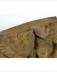 Close-up of brown Sheesham wood carving with intricate patterns and partial human face detail.