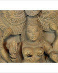 Brown sheesham wood carving of multi-armed deity with ornate headpiece, raised arms, shown indoors.