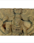 Brown Sheesham wood carving of multi-armed Indian deity with ornate jewelry and peacock-adorned headdress, close-up.