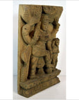 Brown Sheesham wood carving close-up featuring intricate relief of a standing deity with ornate patterns and smaller figure.