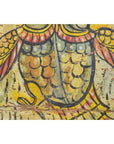 Close-up of colorful hand-painted bird wings and feathers on antique Indian wood shrine in yellow, orange, and black.