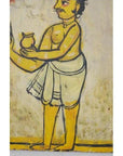 Close-up of antique Indian wood shrine from New Delhi with yellow-skinned figure in white holding small pot.