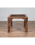 Brown wooden side table with window grate design and turned baluster legs on a wooden floor indoors.