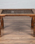 Brown wooden side table with window grate top and turned baluster legs on a wooden floor indoors.