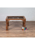 Brown wooden side table with window grate and baluster legs on wooden floor near a color chart.