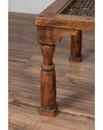 Close-up of brown wooden Indian side table with window grate detail and turned legs on a wooden floor.