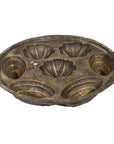 Brown metal antique Indonesian cake mold with six scallop-shaped compartments and two small handles, close-up view.