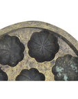 Close-up of antique metal Indonesian cake mold with several flower-shaped cavities, vintage style.