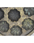 Close-up of a tarnished metal Indonesian cake mold with flower-shaped compartments.