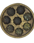 Brown metal Indonesian cake mold with eight flower-shaped indentations and side handles, close-up.