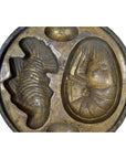 Close-up of an antique metal Indonesian cake mold with lobster and fish-shaped cavities.
