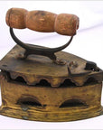 Close-up of antique Indonesian coal iron with brown wooden handle, metal body, vent holes, and compartment.