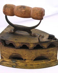 Close-up of antique Indonesian coal iron with brown wooden handle, metal body, vent holes, and compartment.