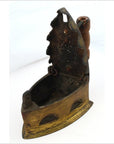 Close-up of antique Indonesian coal iron with rusted metal lid and wooden handle, vintage look.