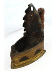 Close-up of antique Indonesian coal iron with rusted metal lid and wooden handle, vintage look.