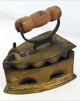 Close-up of antique Indonesian coal iron with wooden handle and vent holes, dark metal finish, vintage style.