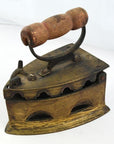 Close-up of antique Indonesian coal iron with wooden handle and vent holes, dark metal finish, vintage style.