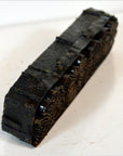 Brown wood antique Indonesian batik stamp block with ornate patterns on white background, close-up view.