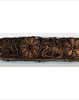 Brown wooden batik stamp block with intricate carved floral and leaf designs, used for Indonesian textile printing.