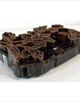 Copper batik ink block with floral design, antique Indonesian style, close-up on white surface for textile printing.