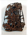 Copper batik ink block with intricate floral patterns and openwork design, antique Indonesian, close-up view.