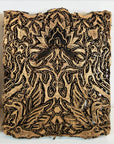 Close-up of three black and gold antique Indonesian copper batik ink blocks with symmetrical floral patterns.