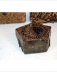 Copper batik ink blocks set with intricate floral and bird designs, close-up on white surface.