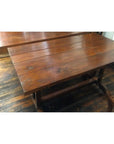 Brown wood antique Indonesian dining table with plank top and sturdy legs, beside matching chair on wooden floor.