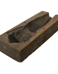 Brown wooden hand-carved Indonesian mold with carved cavity, likely used for casting or shaping objects, on plain background.