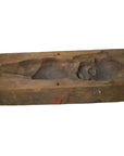 Brown wooden mold with hand-carved top view of a lying baby or child, antique Indonesian craftsmanship, close-up.