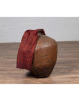Close-up of an antique Japanese brown oil jar with a weathered, irregular shape on a wooden floor.