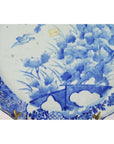 Close-up of blue and white porcelain Japanese hand painted plate with floral and bird design, small price sticker visible.