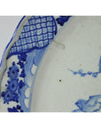 Blue and white ceramic plate with hand painted floral patterns and a bird near the edge, close-up.