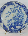 White ceramic Japanese hand painted plate with floral and bird design on a metal stand.