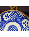 Blue and white ceramic Igezara transferware plate with geometric and floral patterns displayed on a metal stand.