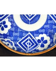 Blue and white ceramic Igezara transferware plate with geometric and floral patterns on a brass stand.
