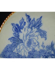 Close-up of blue and white ceramic Igezara Japanese transferware plate with floral design and gold-trimmed edge.