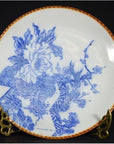 Blue and white ceramic Igezara transferware plate with floral and geometric designs, brown rim, on brass stand.