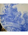 Close-up of blue porcelain Japanese Igezara transferware plate with floral pattern in gold plate holder.