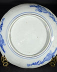 Close-up of the underside of an antique Japanese Igezara transferware plate on a metal stand.