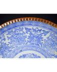 Close-up of blue and white ceramic Japanese Igezara plate with floral patterns and ridged brown glazed edge.