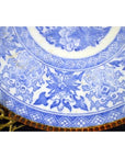 Close-up of blue and white ceramic Japanese Igezara transferware plate with floral and geometric designs on display stand.