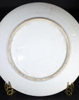 Close-up of the back of an antique Japanese Igezara transferware plate on a gold stand against a black background.