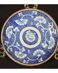 White and blue porcelain Igezara transferware plate on a gold stand, upright display.