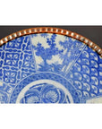 Close-up of blue and white porcelain Japanese Igezara plate with transferware patterns and a scalloped brown edge.
