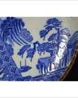 Close-up of blue and white porcelain Igezara plate with transferware landscapes, trees, rocks, and geometric patterns.