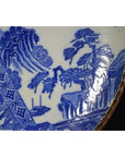 Close-up of blue and white porcelain Igezara plate with transferware landscapes, trees, rocks, and geometric patterns.