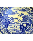 Blue and white porcelain Igezara plate with transferware landscape, trees, buildings, and figures.